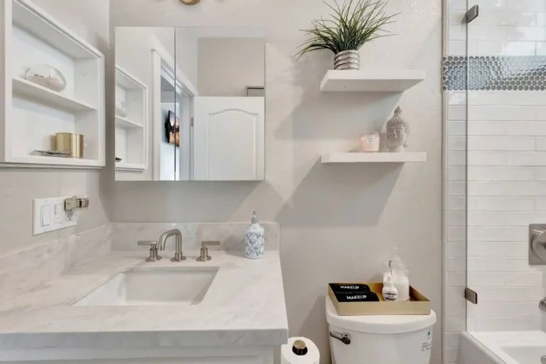 Built in wall niches beside a marble vanity with brushed nickel faucet in a remodeled Newport Beach guest bathroom