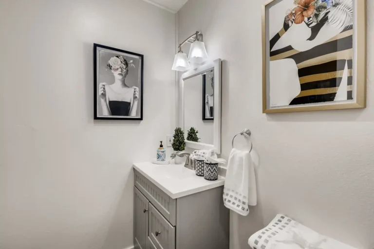 Corner view of the gray vanity with a chrome towel ring and framed prints in a San Clemente guest bathroom