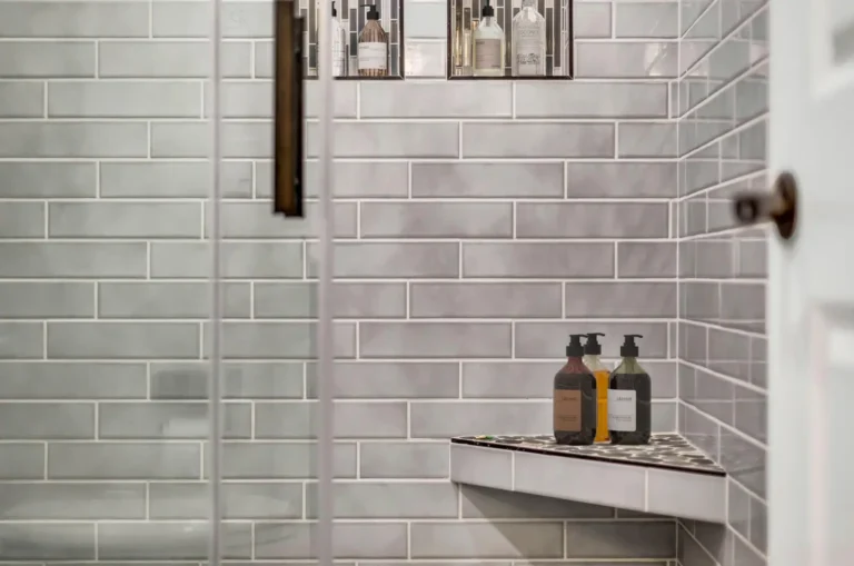 Built-in corner bench topped with pebble tile against gray subway walls in a San Clemente bathroom remodel