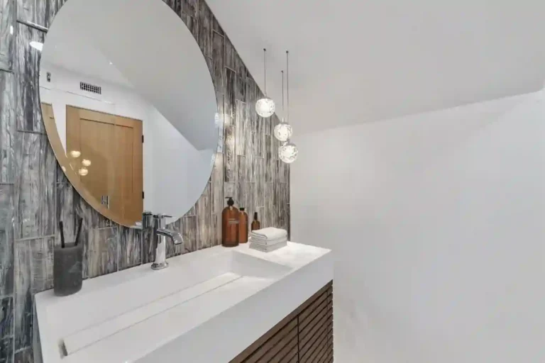 White ramp sink vanity with a round mirror and crystal globe pendants in a Santa Ana guest bathroom remodel