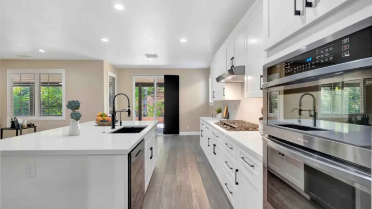 Stainless steel double wall ovens beside white shaker cabinets and a gas cooktop in a remodeled Corona kitchen