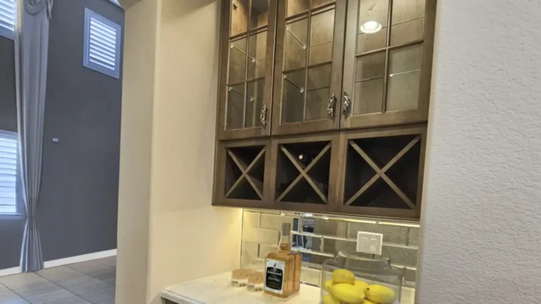 Built-in wine bar with X-shaped wine racks and lighted glass cabinets beside a remodeled kitchen in Costa Mesa