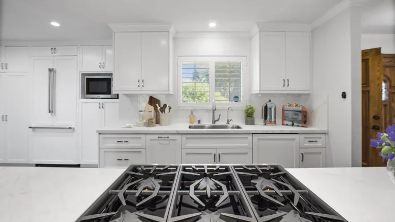 Six-burner gas cooktop on the island facing the white shaker sink wall and slab backsplash in a Laguna Niguel kitchen