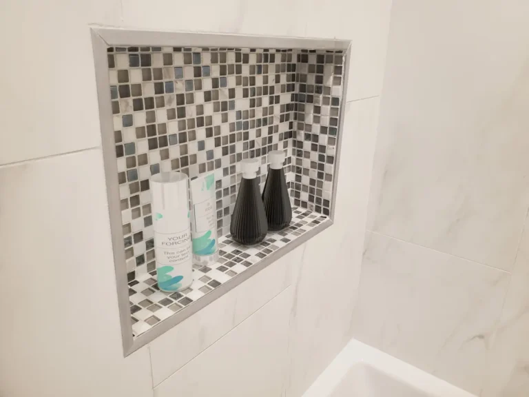Recessed shower niche lined with gray glass mosaic tile and metal trim in a Lake Forest bathroom remodel.