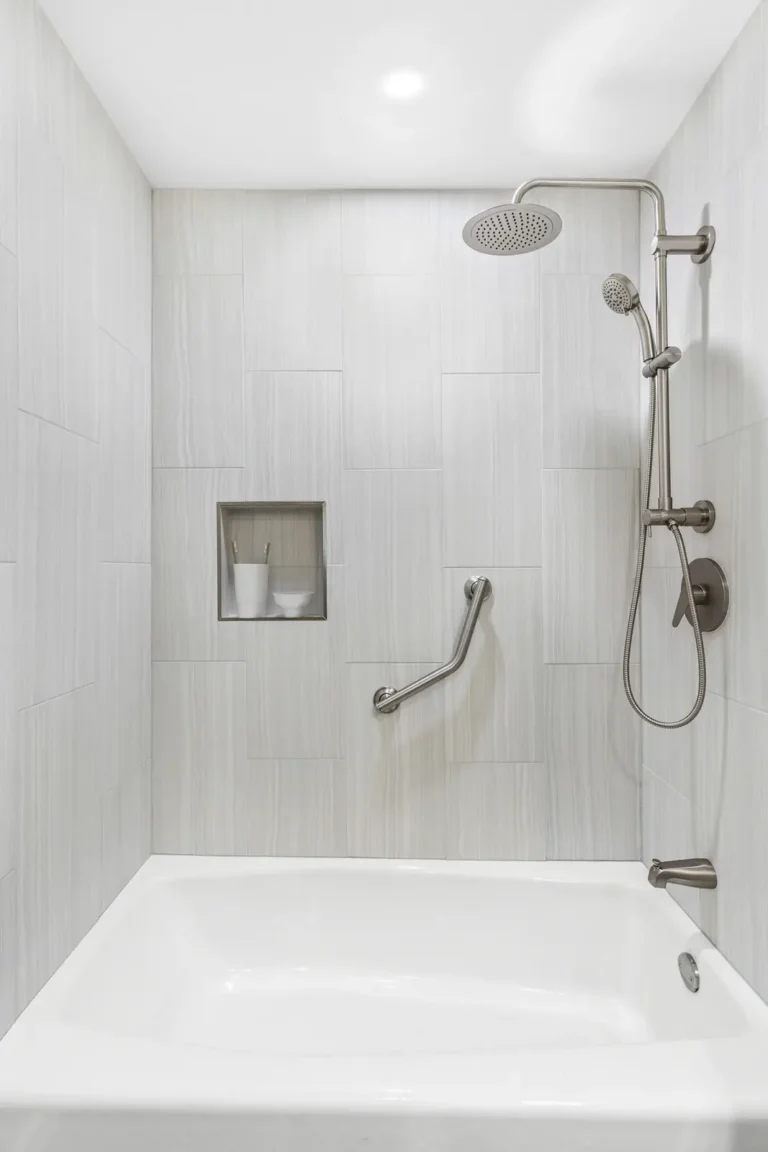 Straight-on view of a tiled tub shower with recessed niche and angled grab bar in a Mission Viejo guest bathroom