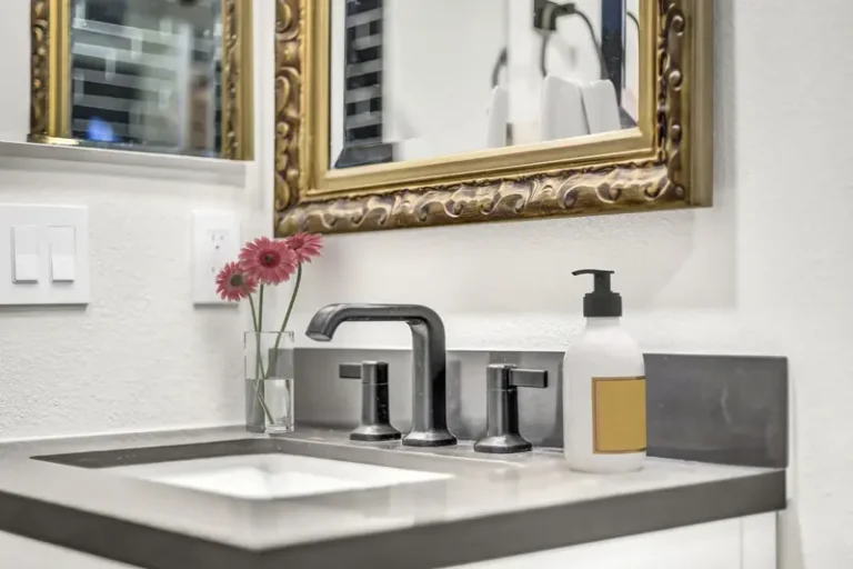 Matte black widespread faucet on a dark stone countertop with undermount sink in an Aliso Viejo bathroom remodel