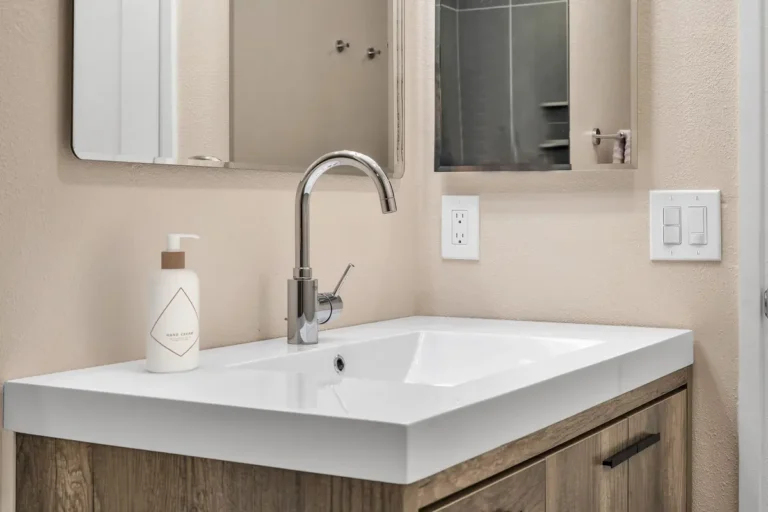 White integrated sink and chrome faucet on a wood-look vanity in a remodeled Carlsbad bathroom