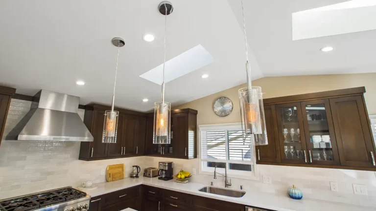 Three glass pendant lights and a skylight on a vaulted ceiling above espresso cabinets in an Irvine kitchen renovation