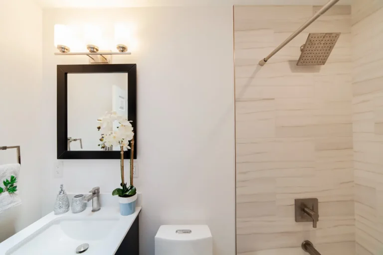 Remodeled Irvine bathroom with a white quartz vanity top, black-framed mirror, and tiled shower with rain head.