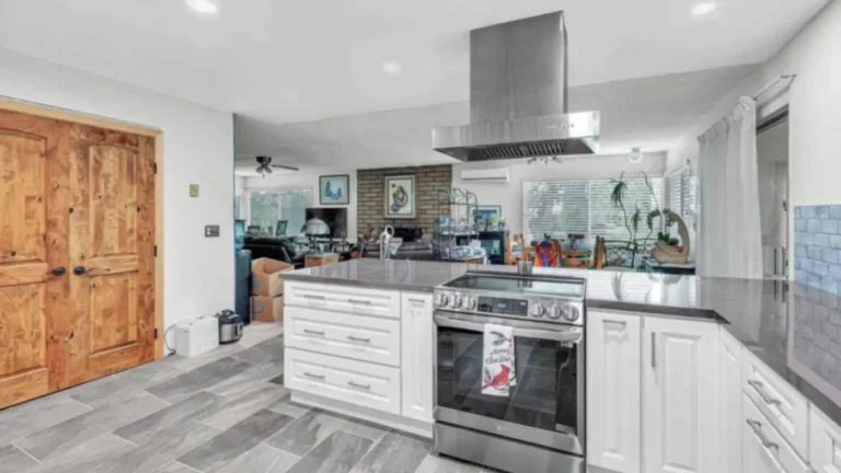 Stainless steel electric range and hood set in a peninsula that opens a Laguna Hills kitchen remodel to the living room