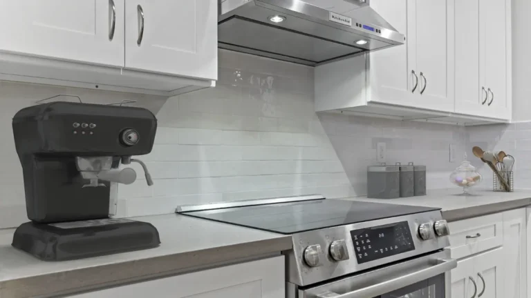 Stainless under-cabinet range hood over a glass cooktop and glossy white tile backsplash in a Laguna Hills kitchen