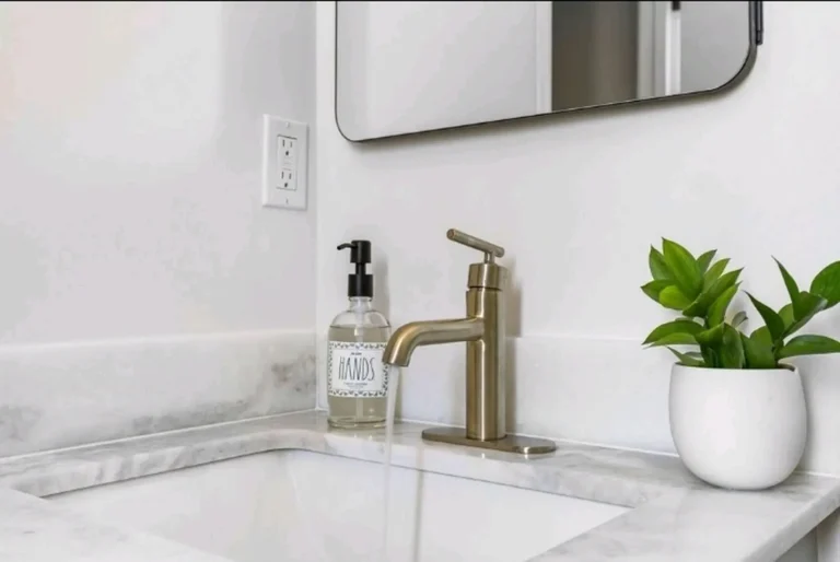 Brushed gold faucet running over an undermount sink set in a marble countertop in a Laguna Niguel bathroom