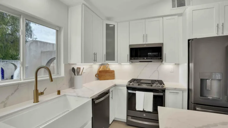 Black stainless gas range and microwave set into white shaker cabinets in a remodeled Oceanside kitchen corner