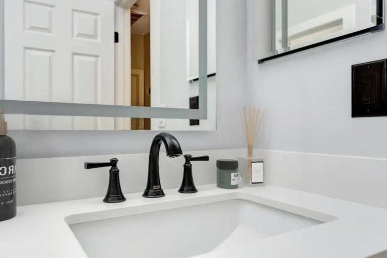 Oil-rubbed bronze widespread faucet set above an undermount sink in a remodeled San Clemente bathroom.
