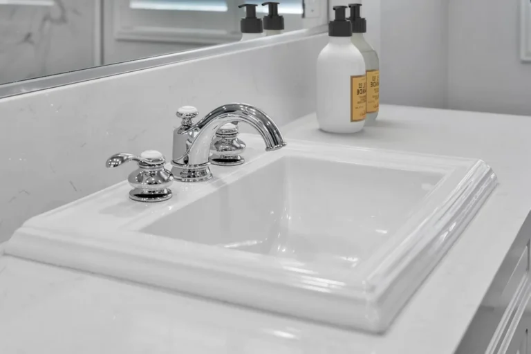 Chrome widespread faucet on a white drop-in sink and quartz countertop in a Carlsbad primary bathroom remodel.