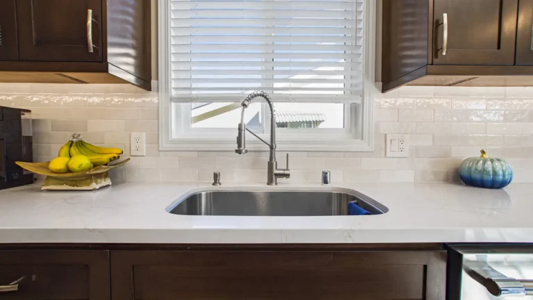 Stainless undermount sink with a pull-down faucet under a window and white quartz counters in an Irvine kitchen remodel