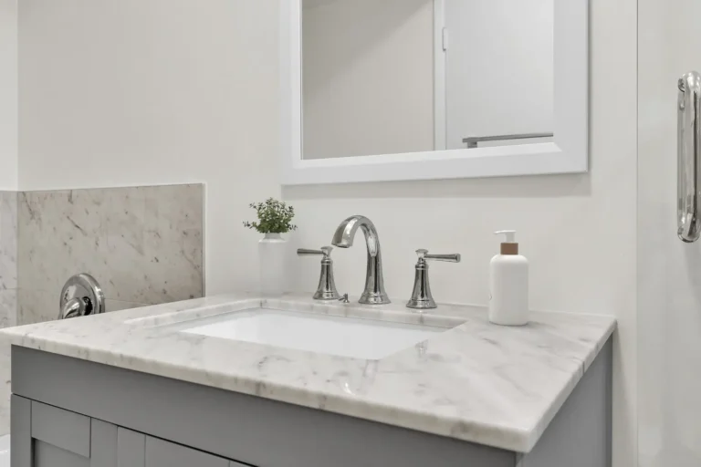 Marble vanity countertop with undermount sink and chrome faucet below a mirrored cabinet in an Irvine bathroom remodel