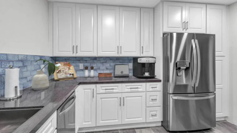 White raised panel cabinets and a stainless French door fridge beside blue tile backsplash in a Laguna Hills kitchen