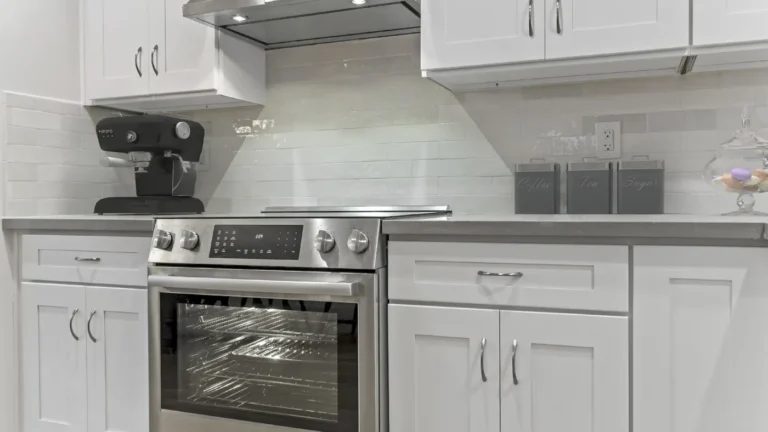 Low-angle view of a stainless range flanked by white shaker base cabinets in a Laguna Hills kitchen remodel