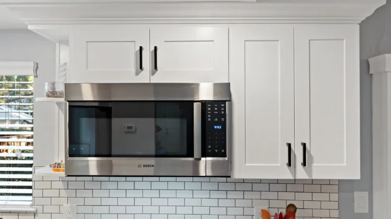 Stainless over-the-range microwave framed by white shaker cabinets and crown molding in a Laguna Niguel kitchen remodel