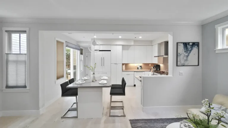 Open kitchen with a quartz island and white gloss cabinets flowing into the living room of a Mission Viejo remodel