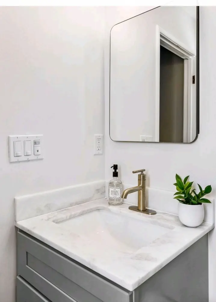 Single gray vanity with a marble top, backsplash, and black framed mirror in a remodeled Laguna Niguel bathroom