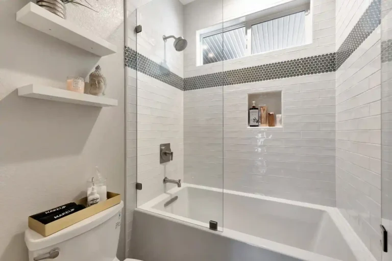 Penny tile accent band wrapping the corner above stacked subway tile in a remodeled Newport Beach guest bathroom