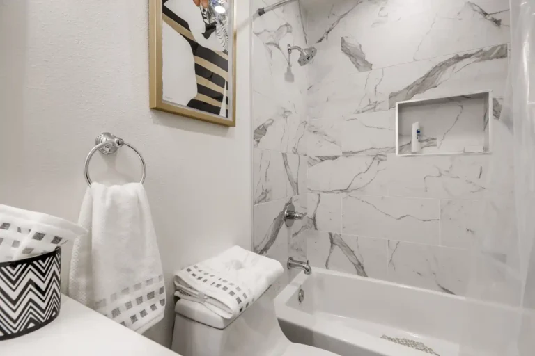 Toilet and towel ring beside the tiled tub surround and shower niche in a San Clemente guest bathroom remodel