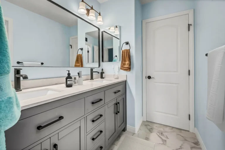 Gray shaker vanity cabinets with matte black hardware and marble look tile flooring in a San Clemente bathroom remodel