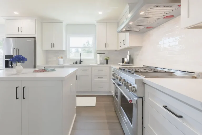 Stainless double-oven range and hood with glossy white subway tile backsplash in a Newport Beach kitchen remodel