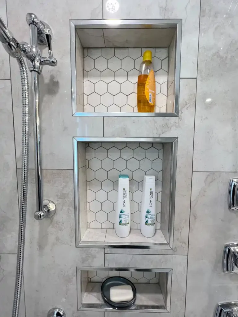 Stacked shower niches with hexagon mosaic backing and chrome trim in a remodeled Aliso Viejo bathroom.