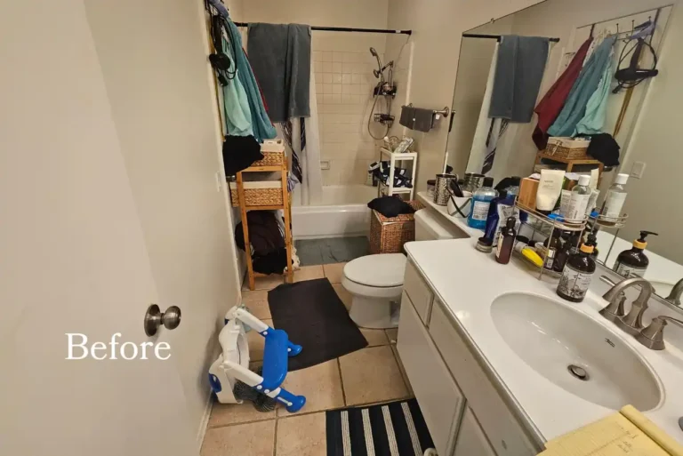 Before photo of the original Carlsbad bathroom with a dated white vanity, beige floor tile, and curtained tub