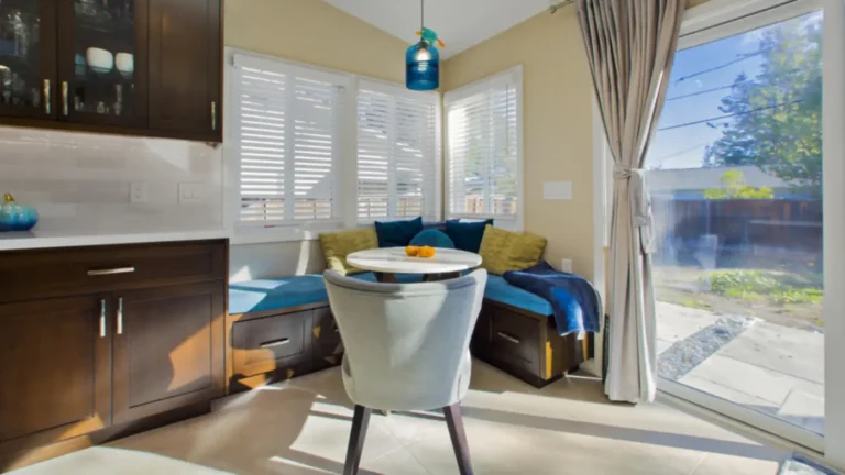 Built-in corner banquette with storage drawers and blue cushions by a sliding patio door in a custom Irvine kitchen