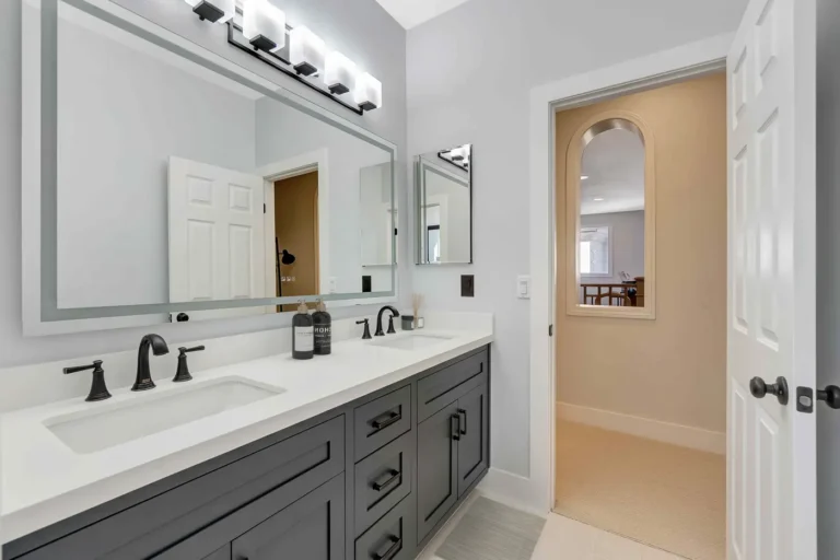 Twin undermount sinks below a wide frosted-edge mirror in a remodeled San Clemente guest bathroom.