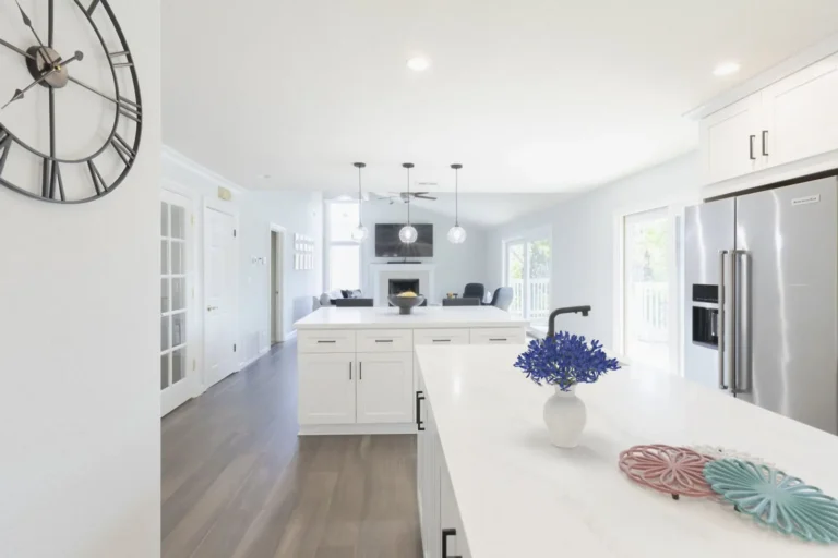 View across a white quartz island to the seating island and open family room with fireplace in a Newport Beach kitchen