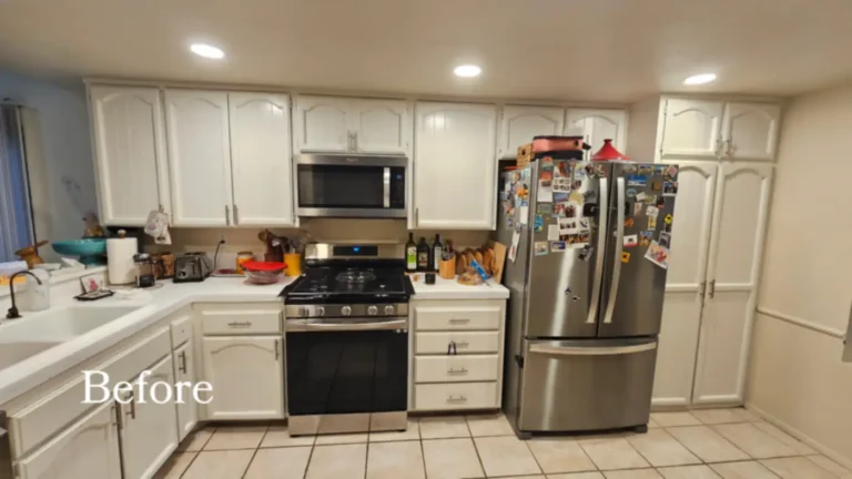 Before photo of a dated Carlsbad kitchen with white arched cabinet doors, tiled countertops, and beige tile flooring