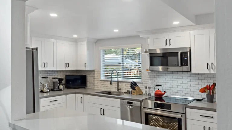 View through the pass-through opening of a U-shaped Laguna Niguel kitchen remodel with white cabinets and subway tile