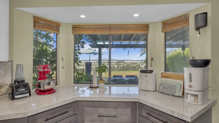 Bay window counter with quartzite surfaces and gray lower cabinets overlooking the yard in an Oceanside kitchen
