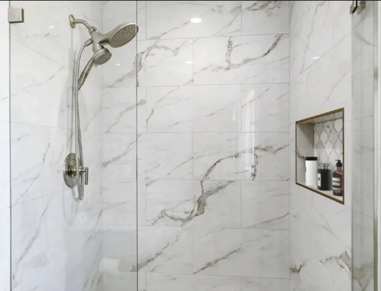 Brushed nickel showerhead and handheld sprayer on a large format marble tile wall in a Laguna Niguel shower