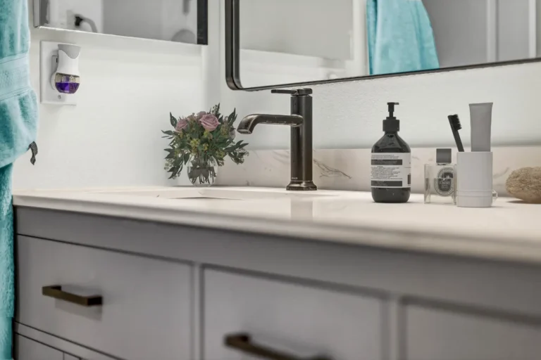 Matte black faucet and undermount sink set in a veined quartz countertop in a San Clemente bathroom remodel