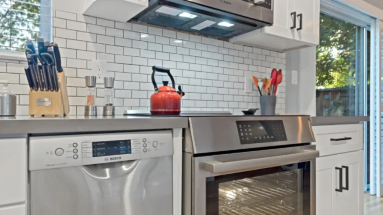 Stainless dishwasher and range under a vented microwave with white subway tile in a Laguna Niguel kitchen remodel