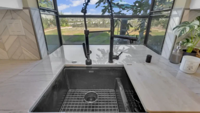 Black undermount sink and spring faucet set in quartzite beneath a garden window in an Oceanside kitchen remodel
