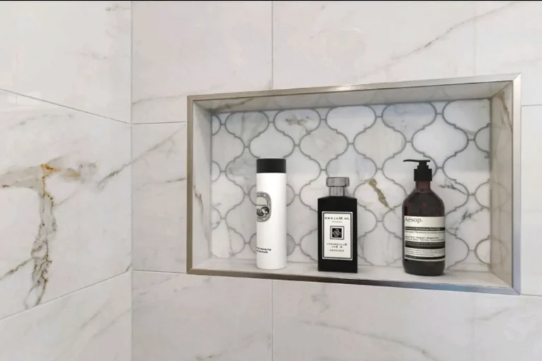 Recessed shower niche lined with arabesque marble mosaic tile and metal trim in a Laguna Niguel bath remodel