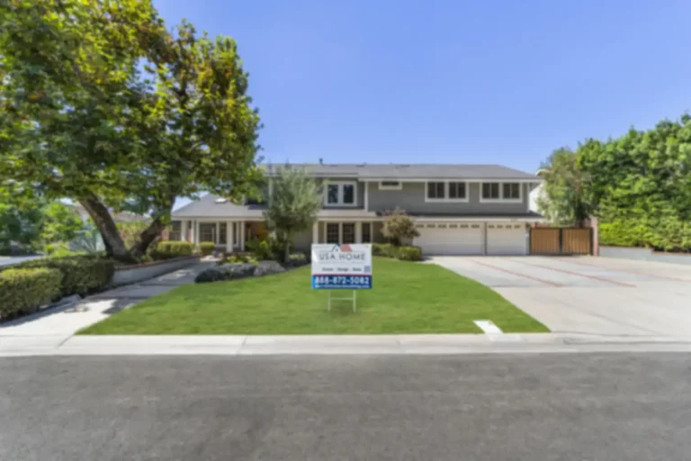 Gray two-story Santa Ana home with new shingle roof, white trim, three-car garage, wood gate, and fresh front lawn.