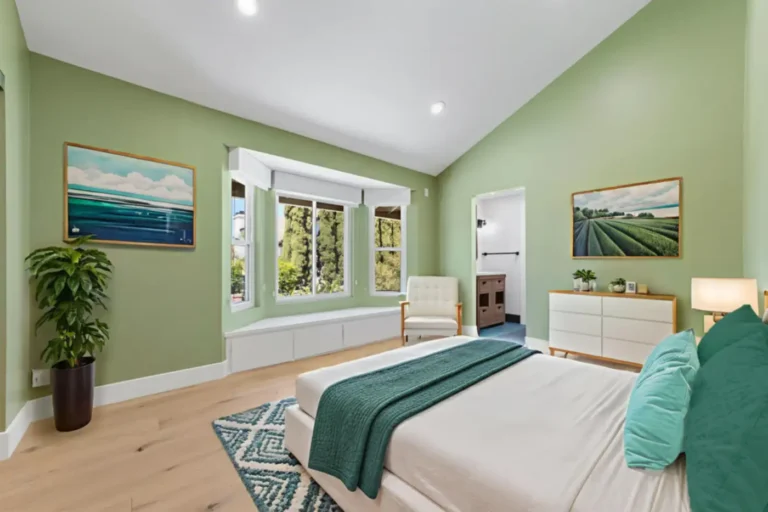 Santa Ana bedroom with sage green walls, vaulted ceiling, bay window with built-in bench seat, and light wood floors.