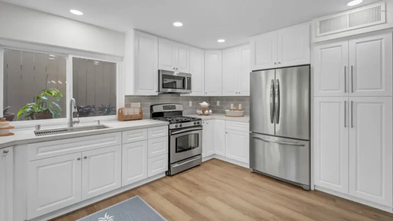 White raised panel cabinets and a French door refrigerator beside a tall pantry wall in a Santa Ana kitchen remodel