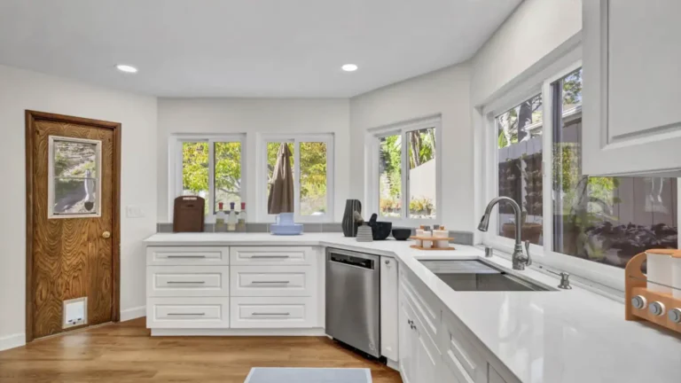 Angled quartz countertop with a workstation sink beneath a wall of windows in a remodeled Santa Ana kitchen