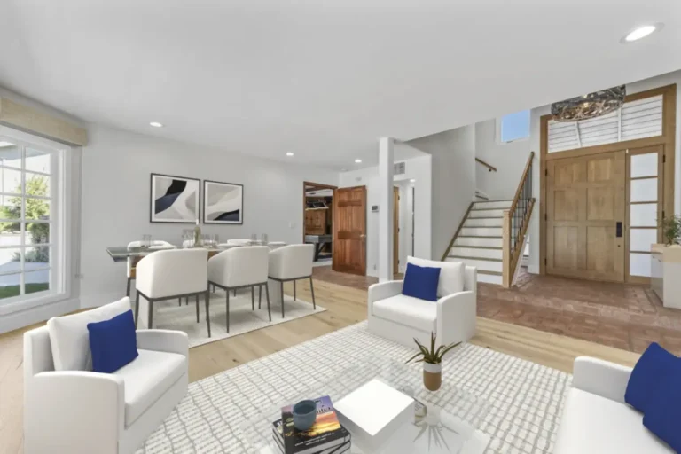 Open Santa Ana living and dining area with light wood floors, wood front door, staircase, and brick paver entry floor.