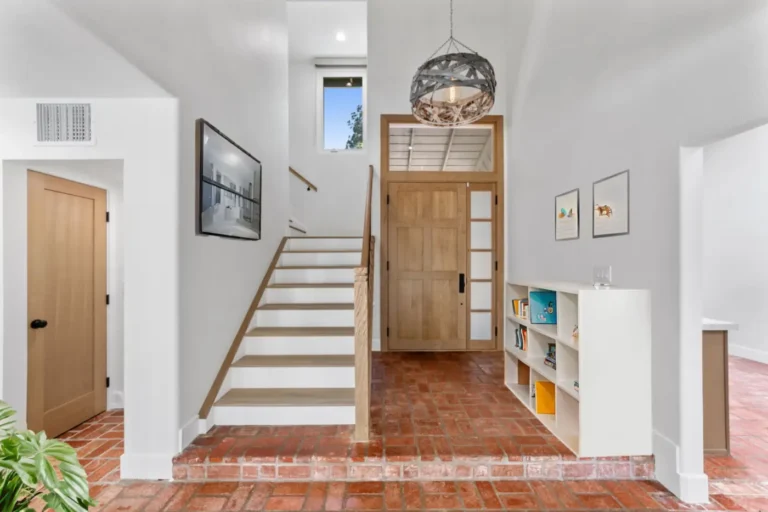 Santa Ana entry with wood stair treads, white risers, a wood front door, brick paver floor, and a metal pendant light.