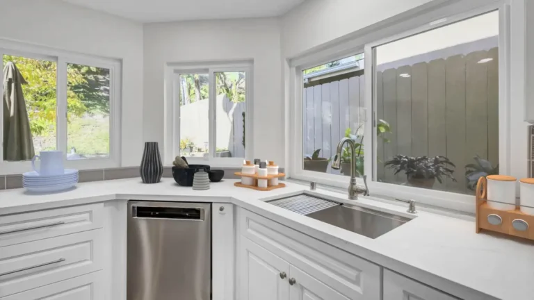 Undermount workstation sink with a pull-down faucet under a wide window in a white Santa Ana kitchen remodel
